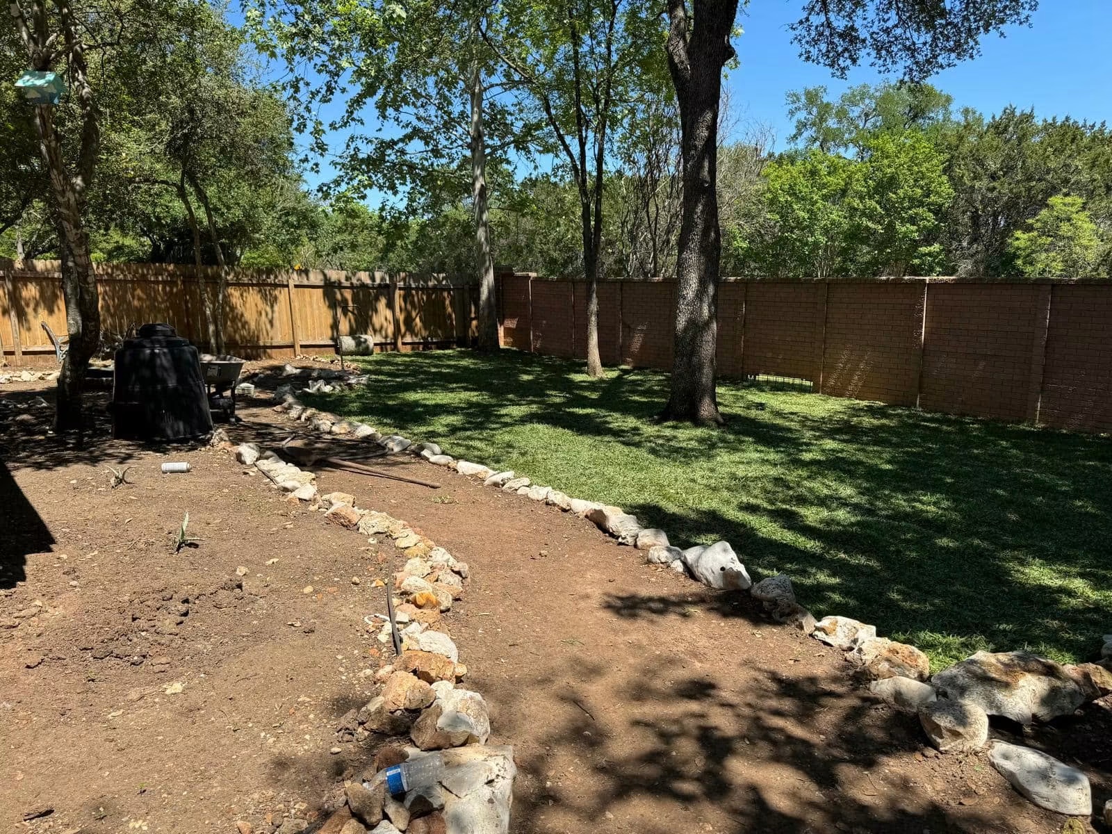 Backyard with shaped planting beds and clean stone transitions during installation