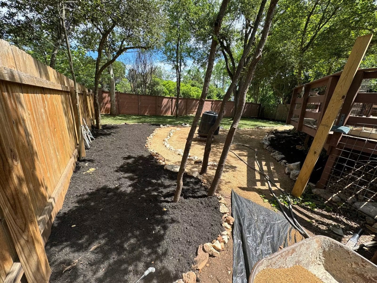 Residential backyard with compacted paths, stone edging, and new mulch in progress